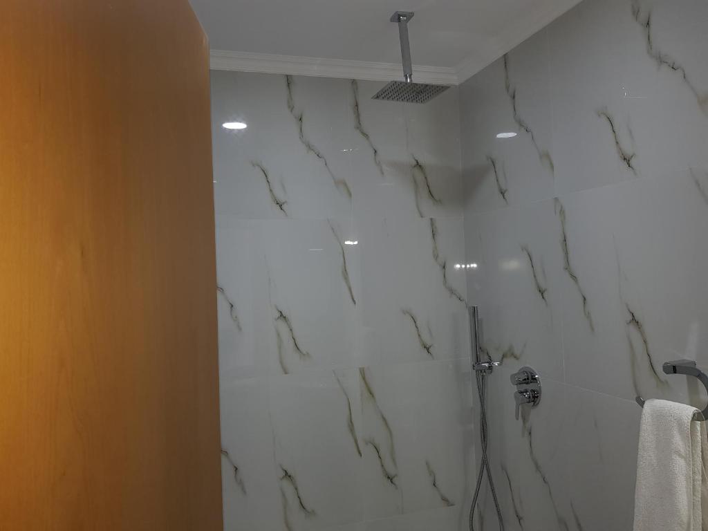y baño con paredes de mármol blanco y ducha. en Hotel Verzaci, en Rinas