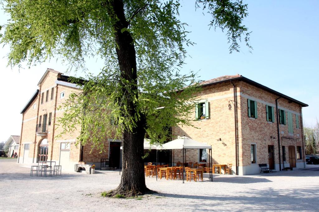 drzewo przed budynkiem ze stołami w obiekcie Agriturismo Le Giarine w mieście Fogliano Redipúglia