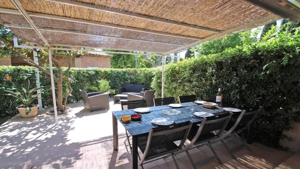 un patio avec une table et des chaises sous une pergola dans l'établissement Bleuets d'Azur, à Sainte-Maxime