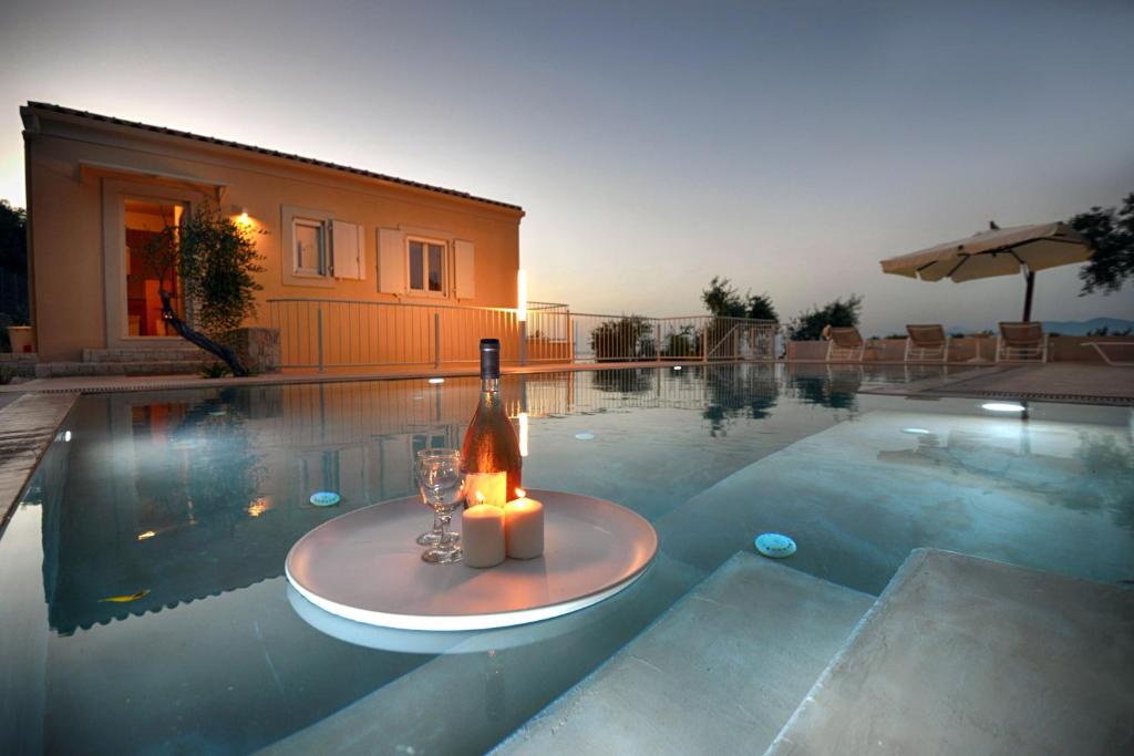 a bottle of wine and a candle on a table in a swimming pool at Villa Dinos in Tranakatika