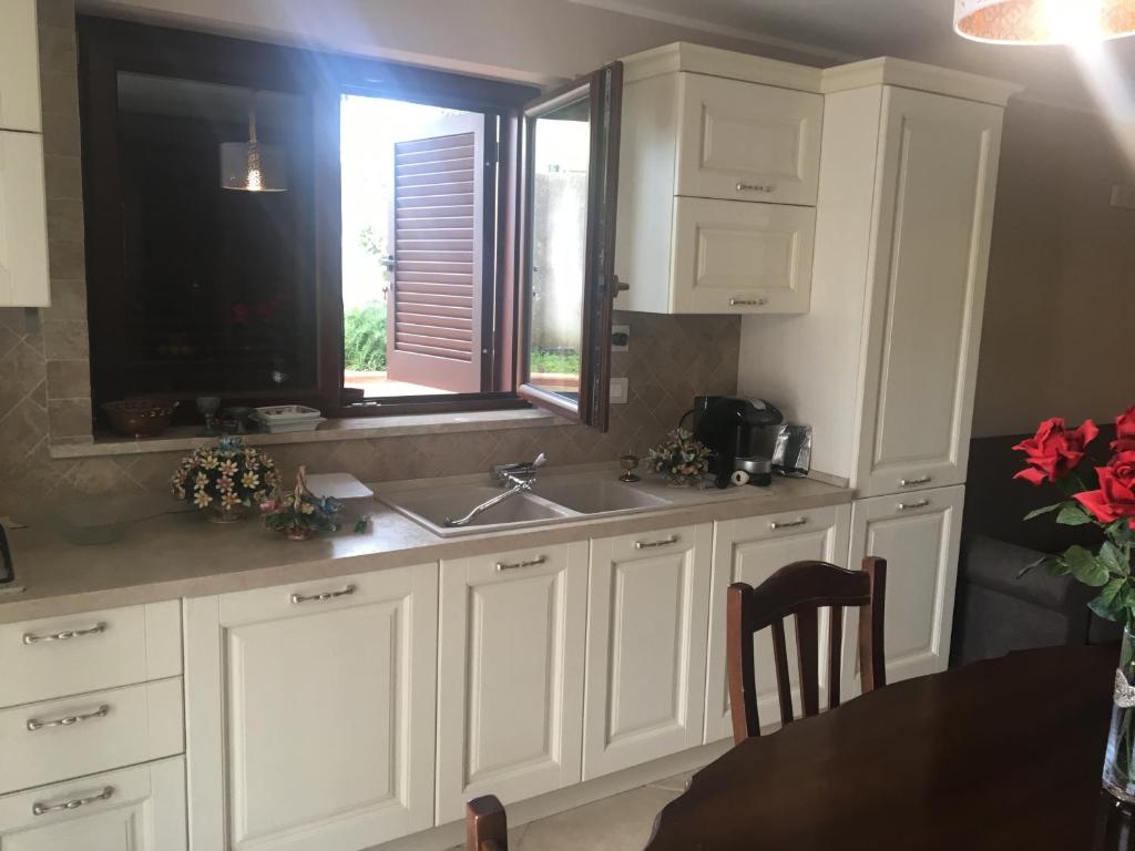 cocina con armarios blancos, fregadero y ventana en Villa Civita, en Gaeta