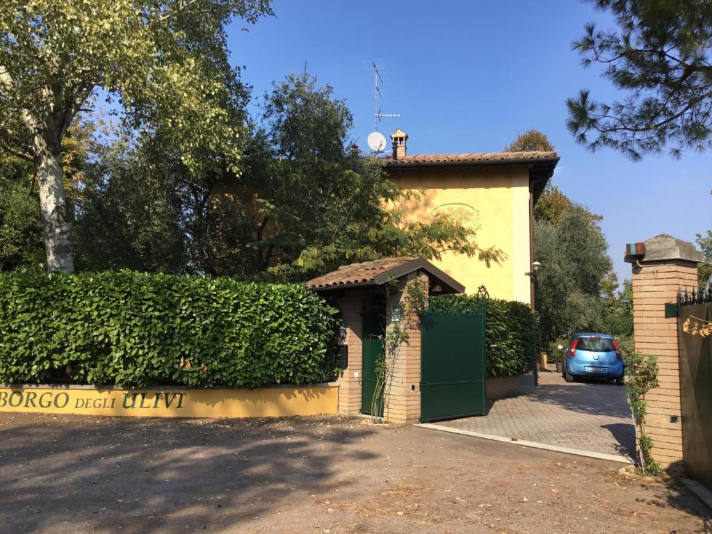 a house with a gate and a car parked in a driveway at Borgo degli Ulivi in Crespellano