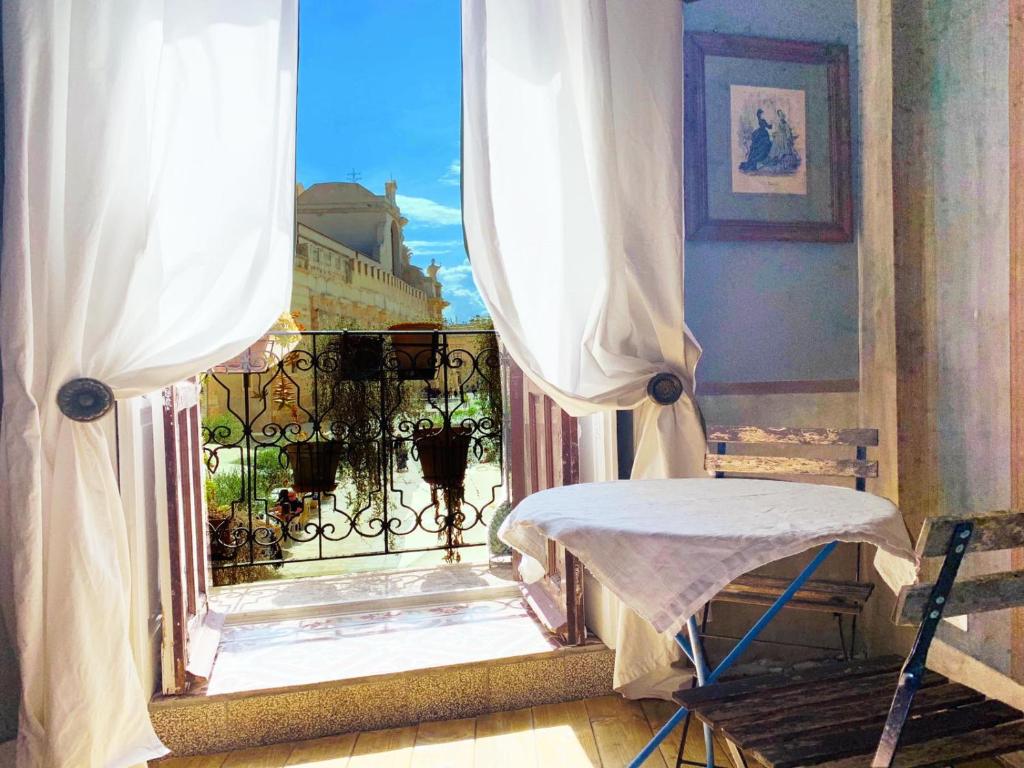 a room with a balcony with a chair and a window at Il Salotto di Maria Pia in Syracuse