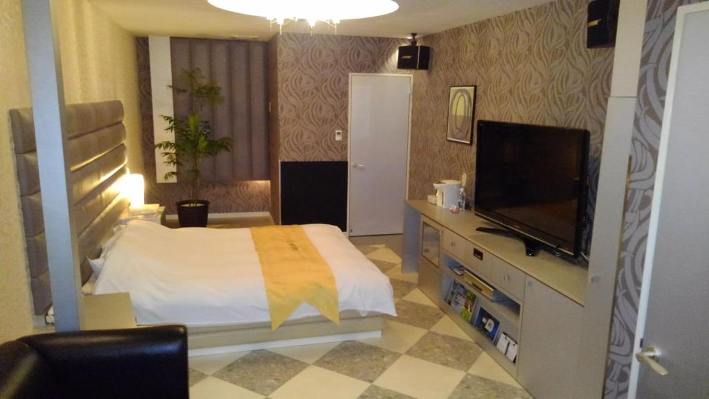 a bedroom with a bed and a flat screen tv at ホテルヴィラコスタ Adult Only 男塾ホテルグループ in Hikone