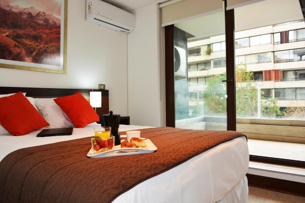 Una habitación de hotel con una cama con una bandeja de comida. en Sunset Aparts, en Santiago