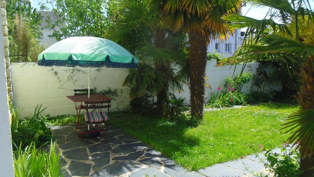 - une table avec un parasol dans la cour dans l'établissement Chambre meublée sympa proche centre ville Lorient, à Lorient