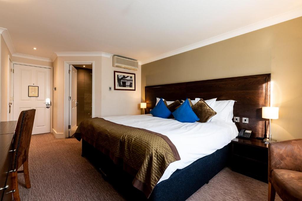 a hotel room with a large bed with blue pillows at Rose And Crown Hotel in London