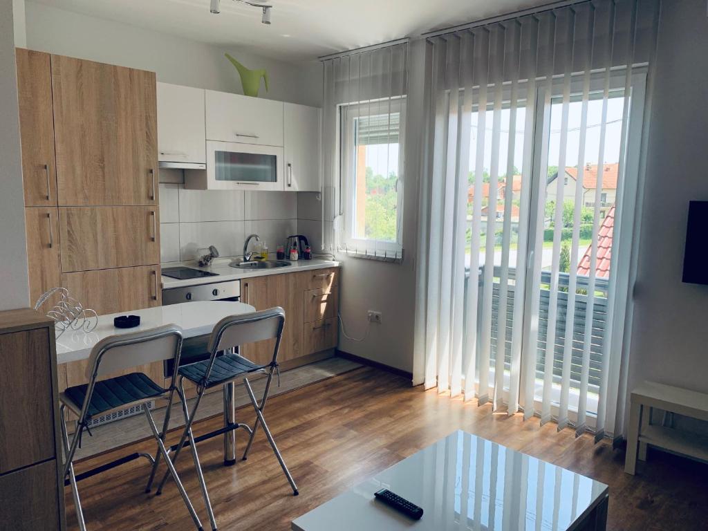 cocina con armarios blancos, mesa y sillas en Maša Studio Apartman en Brčko