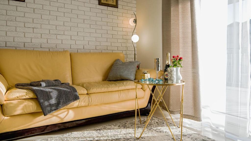 uma sala de estar com um sofá amarelo e uma mesa em Aparthotel Koroni Home em Raszyn