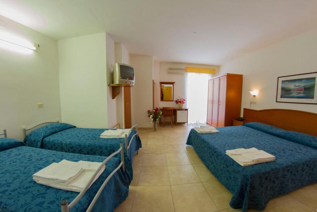 pokój hotelowy z 3 łóżkami i telewizorem w obiekcie Hotel Orchidea w mieście Peschici