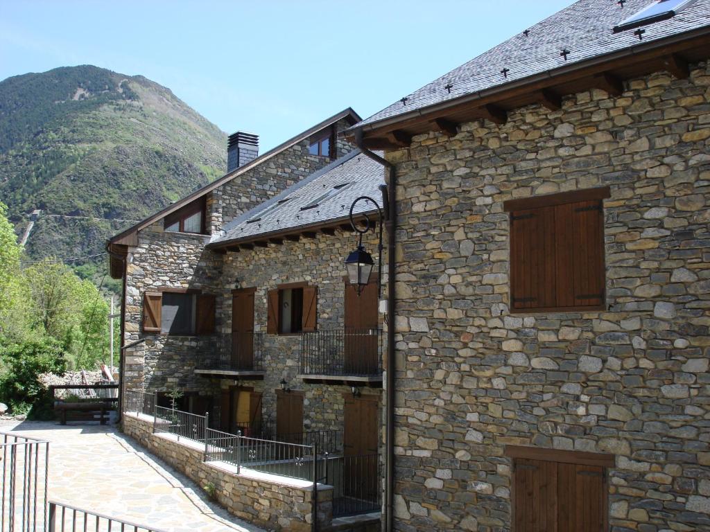 a stone building with a mountain in the background at Apartaments La Peguera II in Barruera