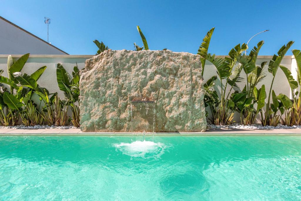 a swimming pool with a large rock in the middle at Acquaviva Suite in Marittima