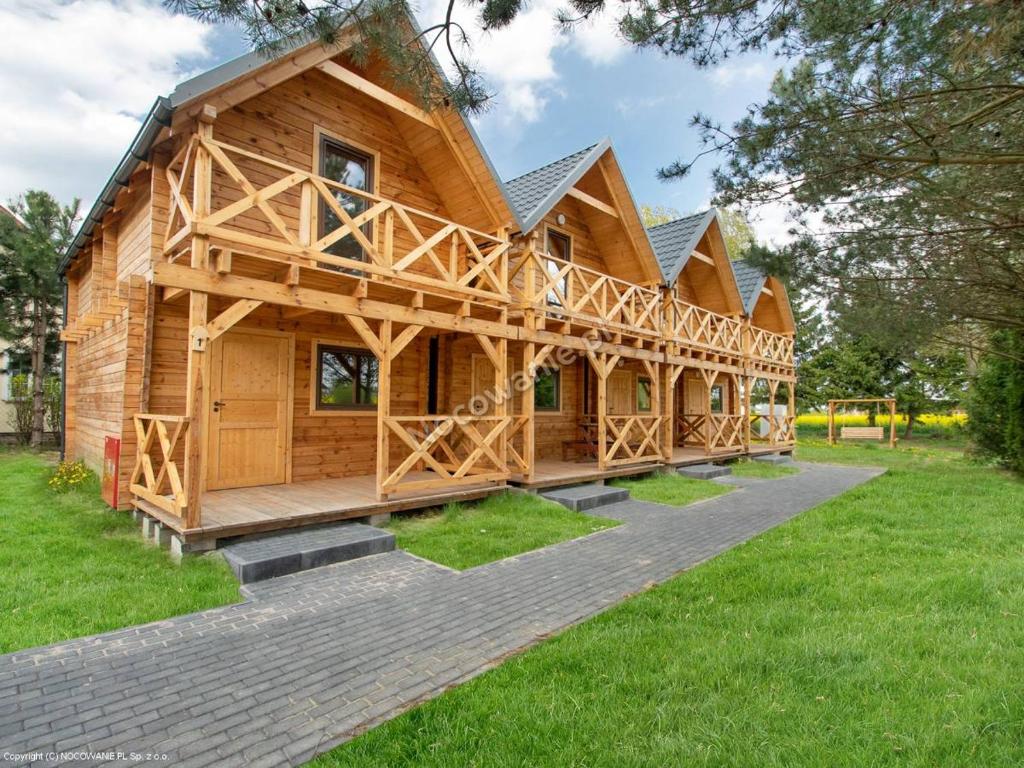 a large wooden house with a wrap around porch at Ustronne Domki in Ustronie Morskie