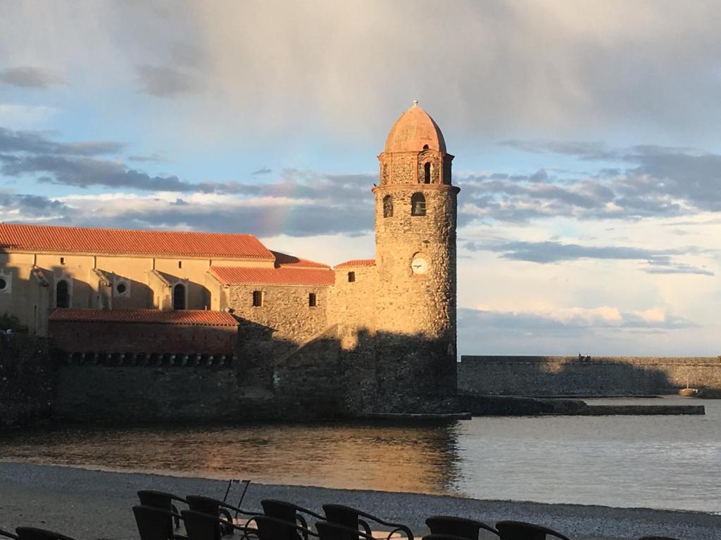 a building with a clock tower next to a body of water at Au coeur de Collioure in Collioure