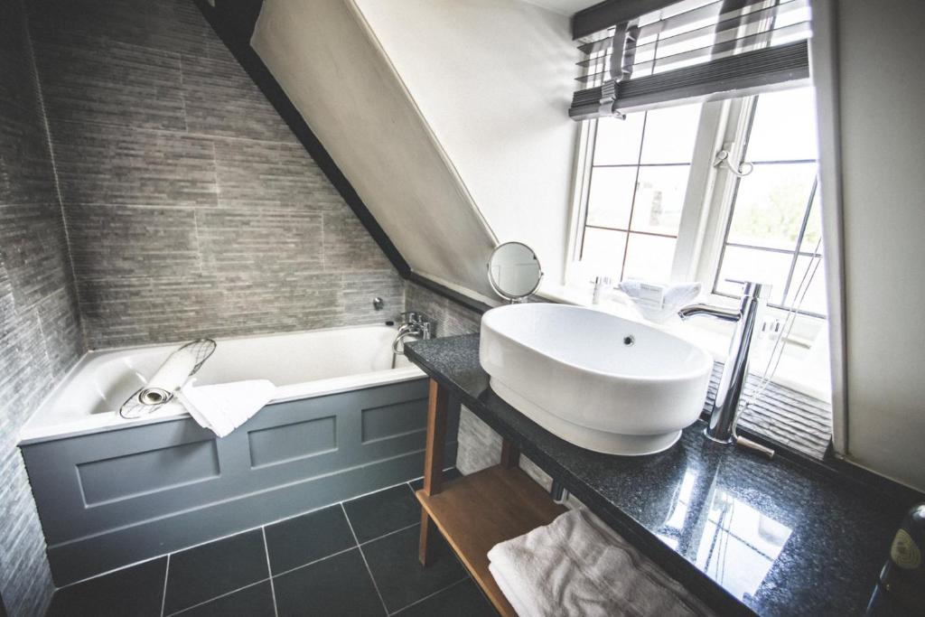 a bathroom with a white tub and a sink at Jeakes House in Rye