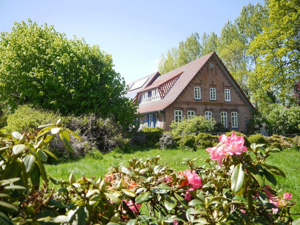 una casa con un jardín con flores delante en Ferienwohnung Warderhof, en Sandstedt