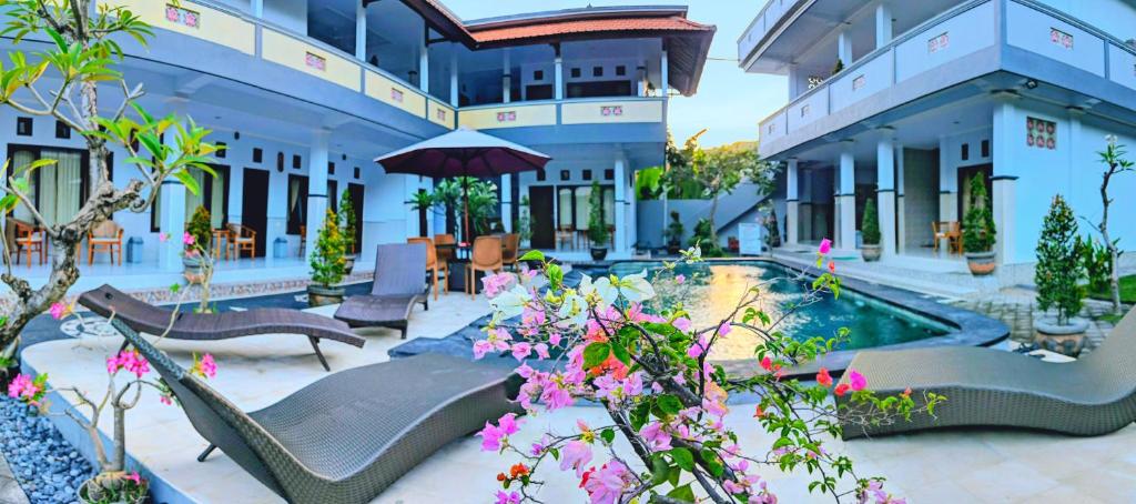 a resort with a pool and chairs and flowers at Serangan Inn Mimba in Padangbai