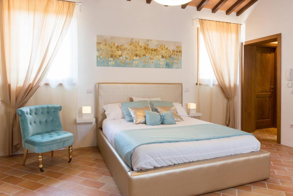 ein Schlafzimmer mit einem Bett und einem blauen Stuhl in der Unterkunft Casa Vacanze Montefalco Il Borgo in Montefalco