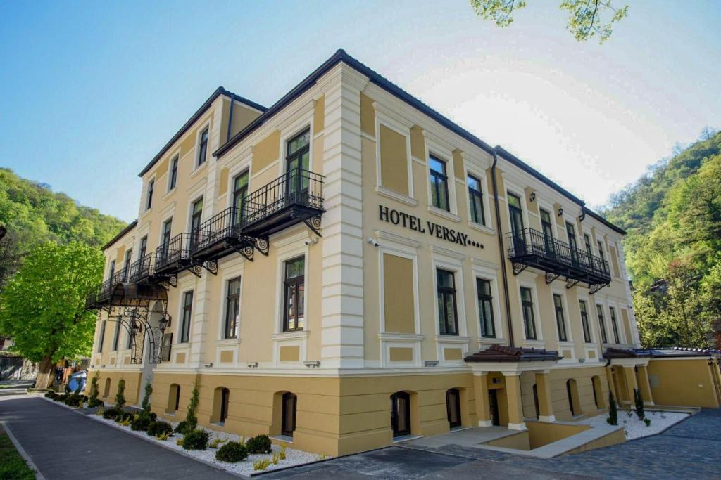 a large yellow building with a hotel room at Hotel Versay in Băile Herculane