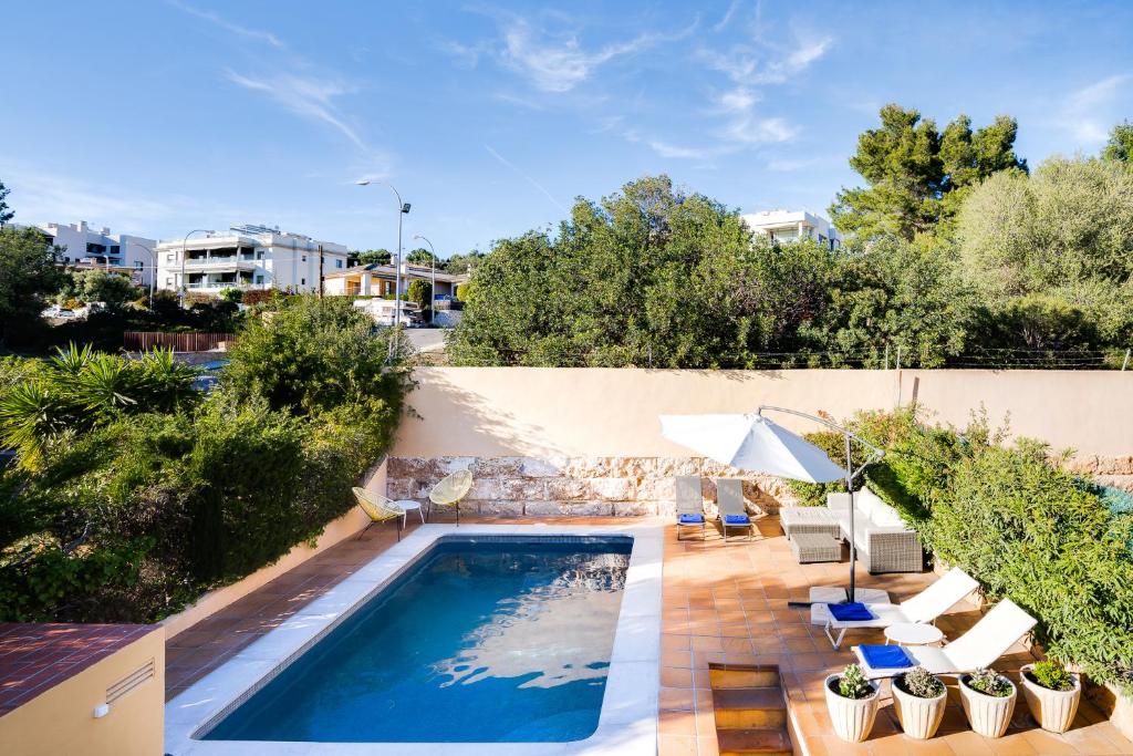 einen Pool im Hinterhof mit Stühlen und einem Sonnenschirm in der Unterkunft VILLA BONANOVA by Priority in Palma de Mallorca