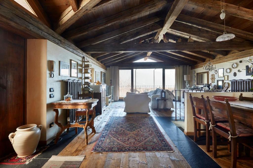 uma sala de estar com tectos em madeira e uma mesa e cadeiras em Il vecchio fienile em Dongo