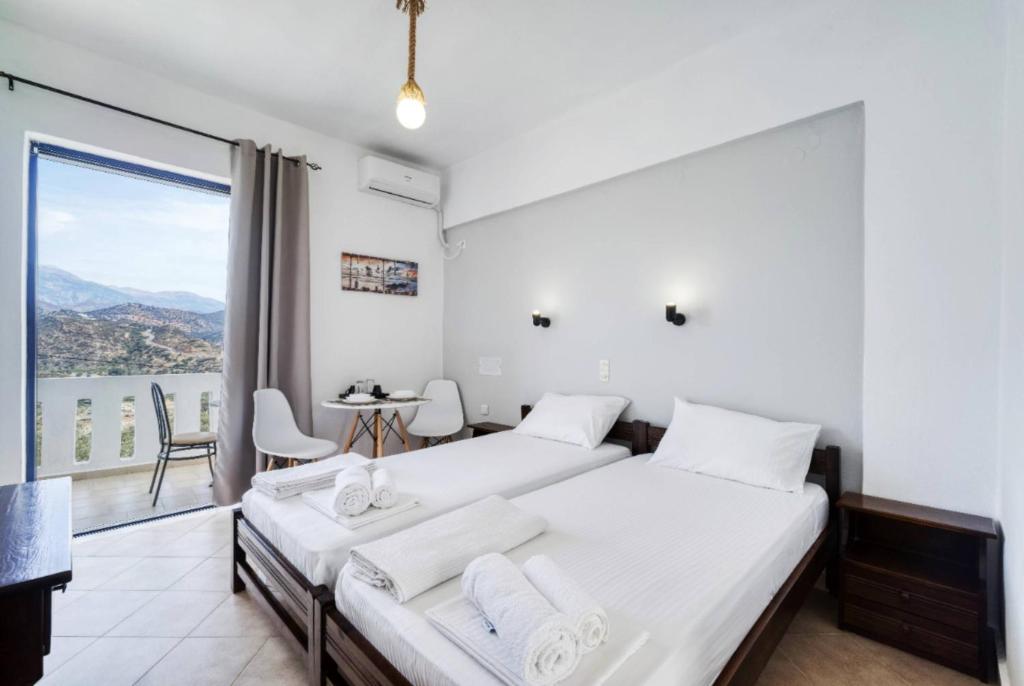 a bedroom with two beds and a table and a balcony at Creta Star Apartments in Agia Galini
