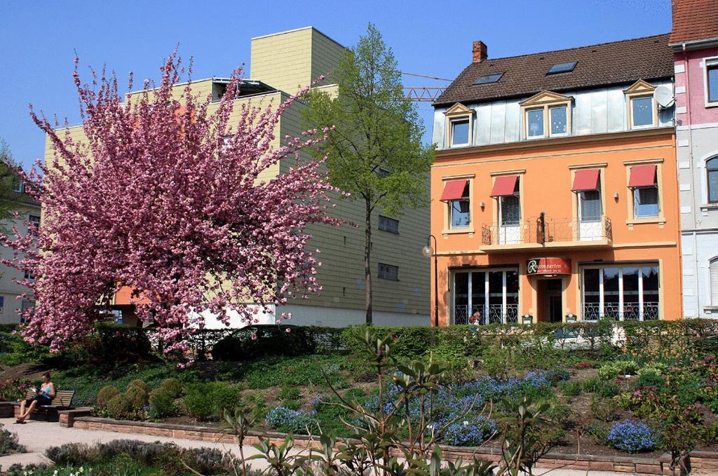 a person sitting on a bench in front of a building at Rosengarten in Kehl am Rhein