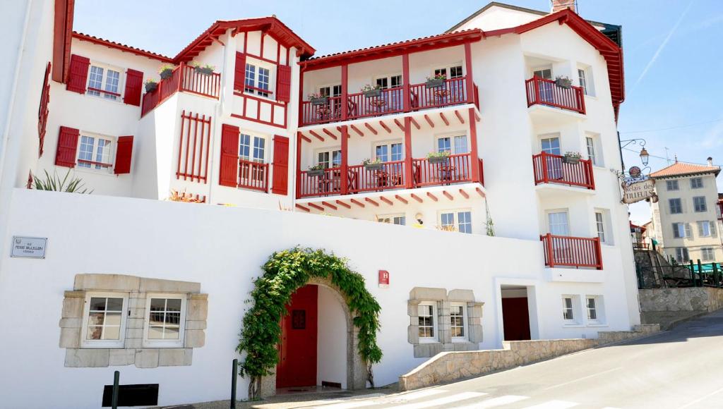 - un bâtiment blanc avec des portes rouges et une arche dans l'établissement Relais Des Tilleuls, à Hasparren