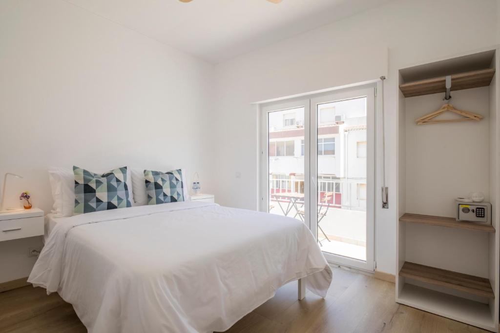 a white bedroom with a bed and a large window at Alto Mar Inn in Lagos