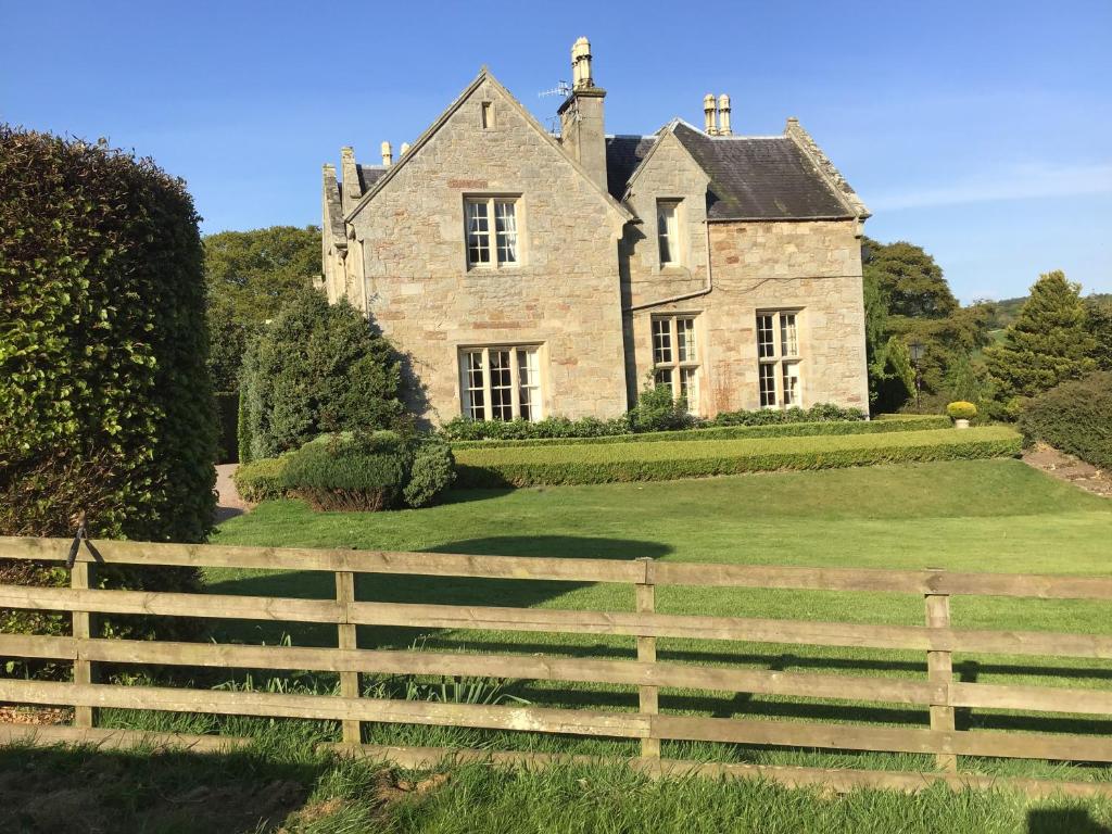 una vieja casa de piedra con una valla delante de ella en Hundalee House, en Jedburgh