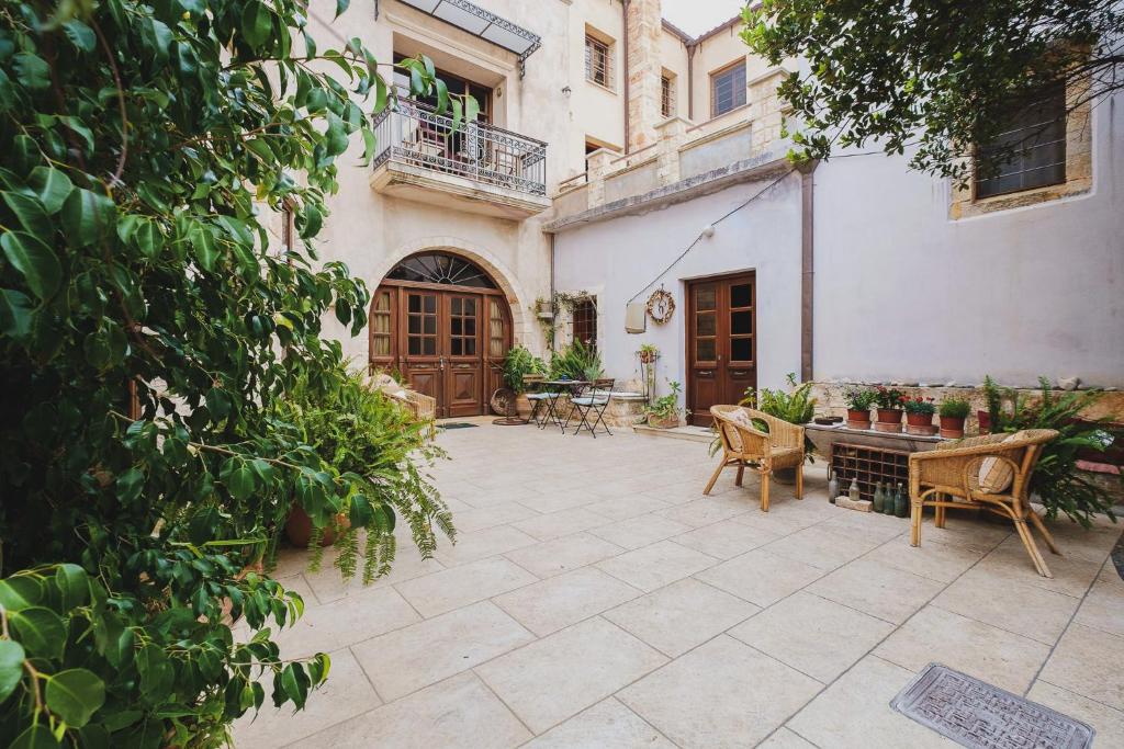 einen Innenhof mit Stühlen, einem Tisch und einem Gebäude in der Unterkunft Iconic Cretan Stone Mansion in Kambánion