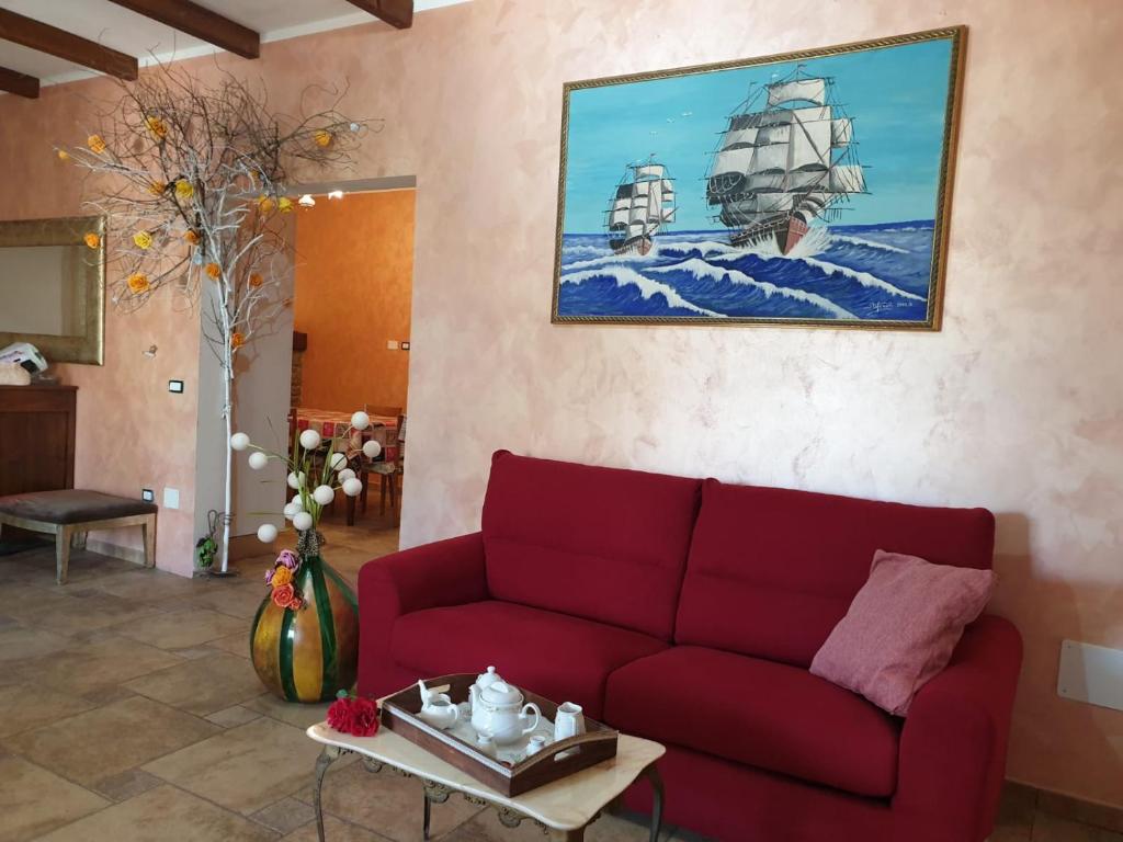 ein Wohnzimmer mit einem roten Sofa und einem Gemälde in der Unterkunft Villa dei Glicini in Parabita