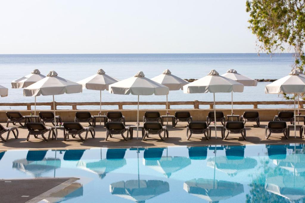 una piscina en la playa con sombrillas y sillas en Harmony Bay Hotel, en Limassol