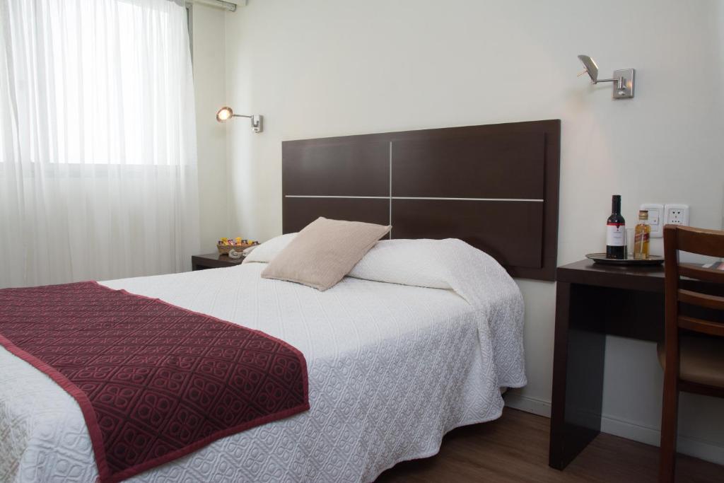 a bedroom with a large bed and a desk at Hotel Europa in Montevideo