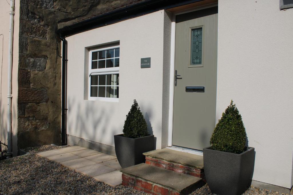 two trees in pots sitting in front of a door at White House Cottages in Durham