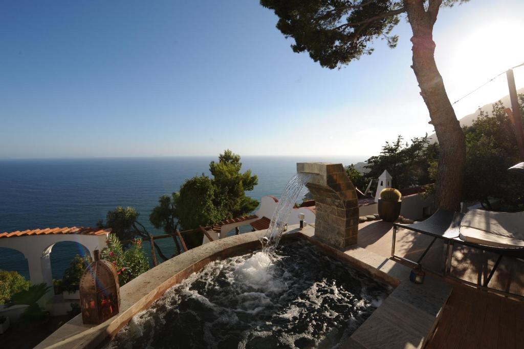 una fuente de agua en un jardín con el océano en el fondo en Claro De Lua Circeo B&B, en San Felice Circeo