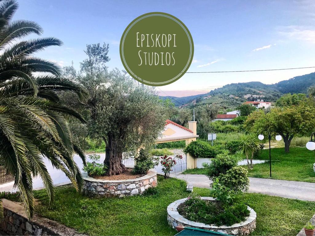 a sign for a property with a palm tree and a house at Pansion Episkopi Studios in Skopelos Town