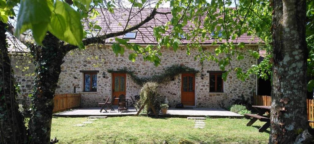 uma casa de pedra com um quintal em frente em Gite du Sorbier em Le Chalard