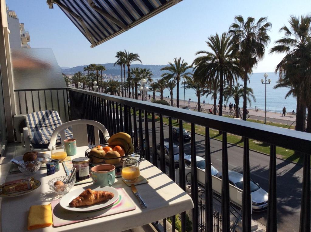 PROMENADE HOLIDAY - CARIATIDE PROMENADE SEA VIEW في نيس: طاولة مع طبق من الطعام على شرفة مع الشاطئ