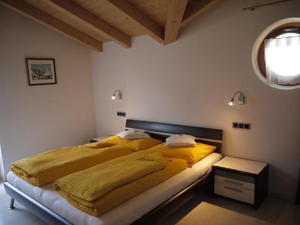 a bedroom with two beds with yellow blankets and a window at Hörtmairhof in Campo Tures