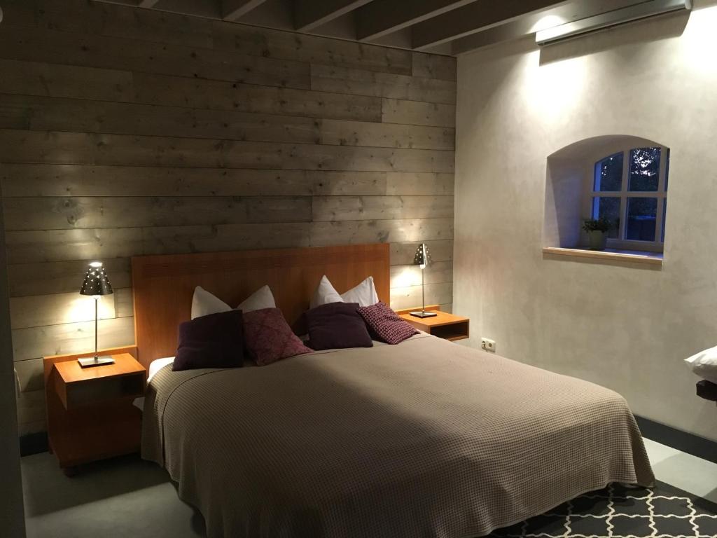 een slaapkamer met een groot bed en 2 lampen op tafels bij B&B bij Bedaf in Uden