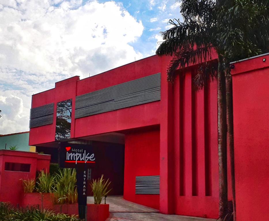 um edifício vermelho com um sinal em frente em Impulse Motel em São Bernardo do Campo