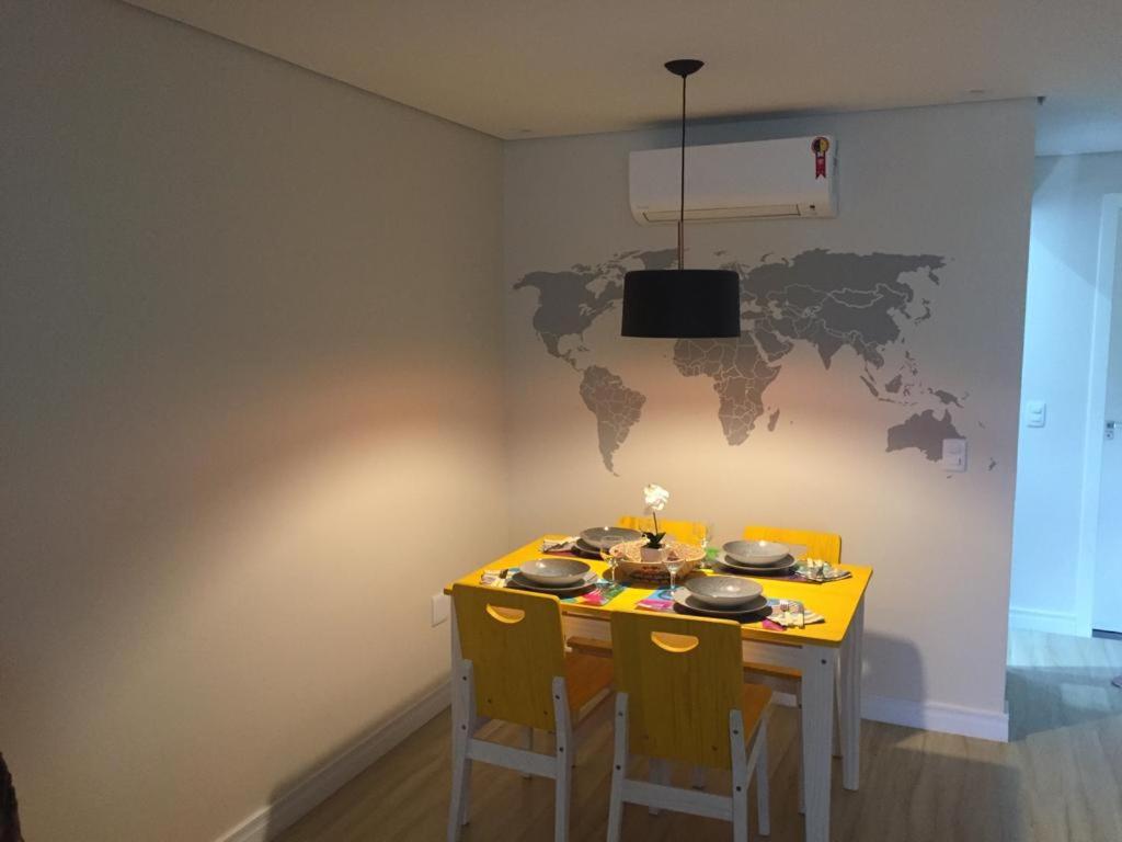 Charmoso e Confortável في برازيليا: طاولة غرفة طعام مع كراسي وخريطة عالمية على الحائط