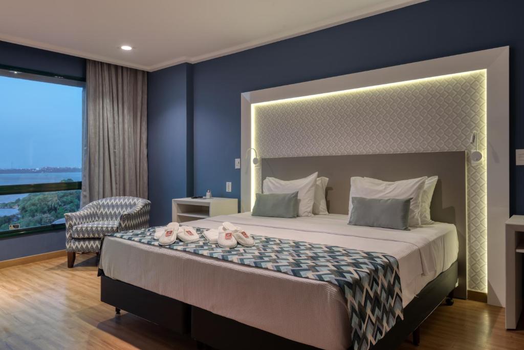 a bedroom with a large bed with a large window at Comfort Suítes Vitória in Vitória