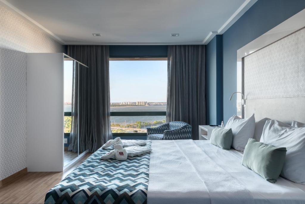 a bedroom with a large bed with a large window at Comfort Suítes Vitória in Vitória