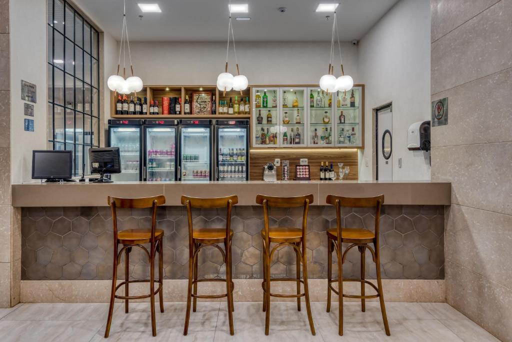 a bar in a restaurant with four bar stools at Comfort Suítes Vitória in Vitória