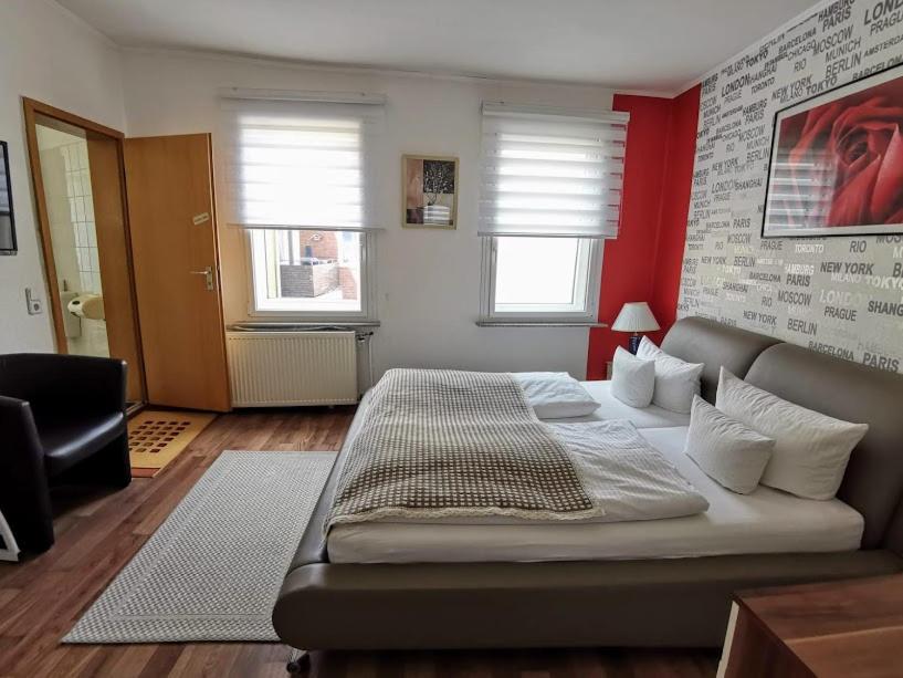 ein Schlafzimmer mit einem großen Bett und einer roten Wand in der Unterkunft Hotel Happy in Bad Bramstedt