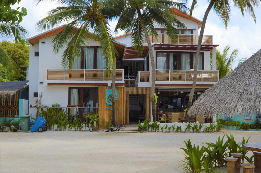 a building with palm trees in front of it at Kinan Retreat in Fulidhoo