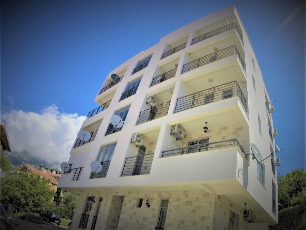 un edificio blanco con ventanas y balcones. en Apartments Becici, en Budva