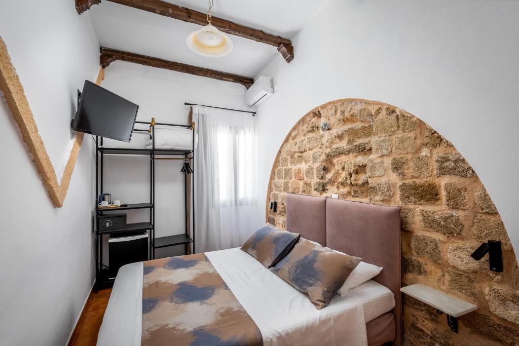 een slaapkamer met een bed en een bakstenen muur bij Casa De La Sera in Rhodos-stad